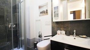 Een moderne badkamer met een douchecabine van glas, een witte wastafel en een spiegel boven de wastafel.