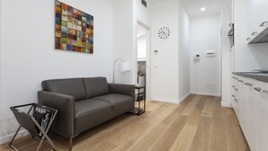 A modern living room with a grey sofa, a colorful abstract painting, a small side table, and a bookshelf. - Italianway Easy - Segrino 6 (Milan)