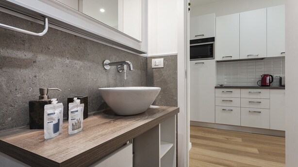 A modern kitchen with a large white sink, wooden countertop, and white cabinets. - Italianway Easy - Segrino 6 (Milan)