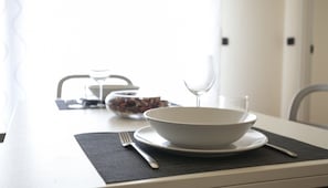 Une table à manger avec un bol blanc, un verre à vin et une fourchette posés sur un set de table noir.