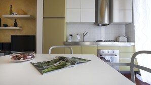 A modern kitchen with a white table, a magazine, and a bowl of food. - Italianway Comfort - Spadolini 6 (Milan)