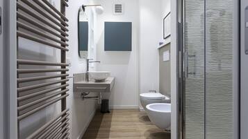 Un baño moderno con inodoro, bidé y lavabo con espejo superior.