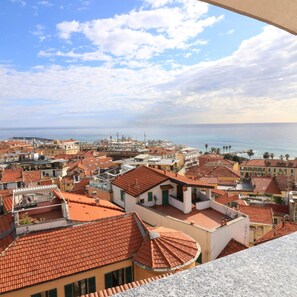 A coastal cityscape with red-tiled rooftops and buildings with balconies, overlooking the sea. - Sn-cost8a4 - Costiglioli 8 (Sanremo)