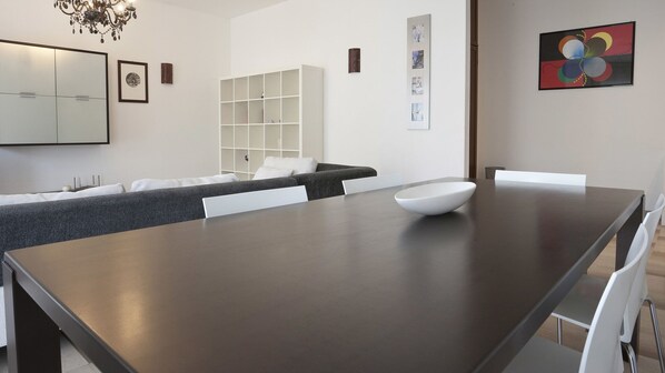 A modern dining area with a dark wooden table, white chairs, and a white bowl.