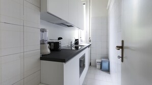 A modern kitchen with white tiles, a black countertop, a blender, a toaster, and a sink. - Italianway Easy - Argonne 39 (Milan)