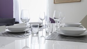 A dining table set with white plates, bowls, and clear glasses, reflecting on a glossy surface. - Italianway Easy - Argonne 39 (Milan)