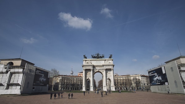 A large open plaza with an ornate archway in the center, surrounded by historic buildings.