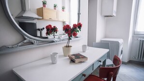 A modern kitchen with a white countertop, a book, a vase with red flowers, and a mirror reflecting the room. - Italianway Easy - Corso Sempione 96 (Milan)