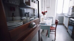 A kitchen with a stove, cabinets, and a dining area with a table and chairs. - Italianway Easy - Corso Sempione 96 (Milan)