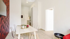 Un comedor moderno con una mesa blanca, sillas traslúcidas y un sofá rojo.