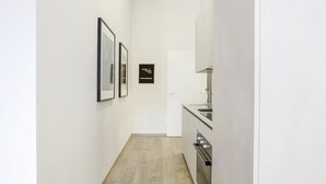 Un pasillo con obras de arte enmarcadas en las paredes, un cartel de bienvenida y una zona de cocina con fregadero y horno.
