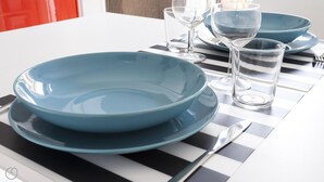 A dining table with blue plates, clear glasses, and a striped placemat. - Italianway Easy - Lambertenghi 3 (Milan)
