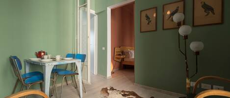 Un comedor con una mesa y sillas, un tapete de cuero de vaca y cuadros con imágenes de aves en la pared.