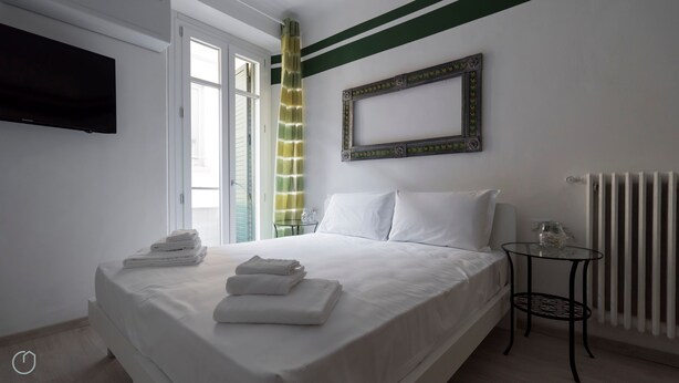A hotel room with a bed, a television, a radiator, and a small table.