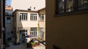 A courtyard with a dining area, potted plants, and a building with multiple windows and balconies.