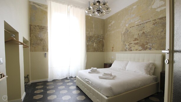A bedroom with a bed, a nightstand, a hanging light fixture, and a door. - Italianway Easy - Melzo 12 - Vintage (Milan)