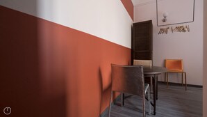 Ein moderner Raum mit einem runden Tisch, zwei Stühlen, einem Holzkasten und einer Wandleuchte.
