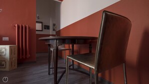 Ein Zimmer mit einem runden Tisch, einem Stuhl, einem Heizkörper und einer Tür mit Lichtschalter.