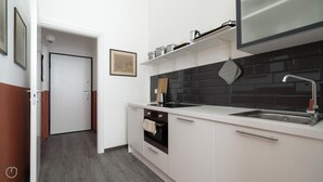 Eine moderne Küche mit weißen Schränken, einer schwarzen Küchenrückwand, einer Edelstahl-Spüle und einem eingebauten Backofen.