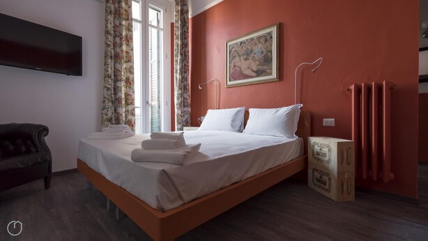 Ein Hotelzimmer mit Bett, Wandfernseher, einem Gemälde und einem Vorhangfenster.
