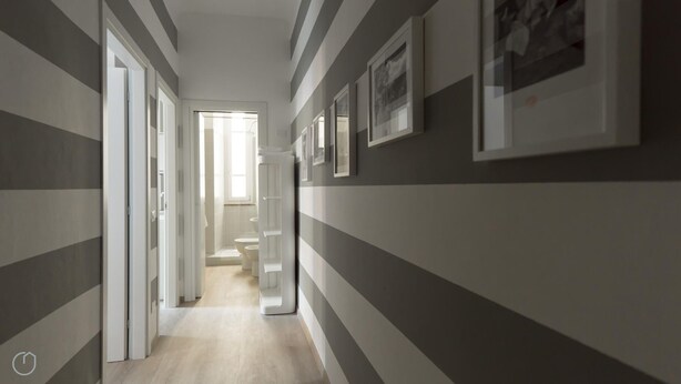 A hallway with striped walls, a door leading to a bathroom, and framed pictures on the wall. - Italianway Easy - Melzo 12 - Righe (Milan)