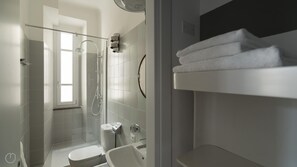 A modern bathroom with a glass-enclosed shower, a toilet, and a sink.