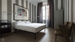 A bedroom with a bed, a desk, a chair, a window with curtains, and a wall-mounted artwork. - Italianway Easy - Melzo 12 - Righe (Milan)