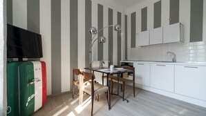 A modern kitchen with striped wallpaper, a dining table with chairs, a TV on a cabinet, and a coffee maker. - Italianway Easy - Melzo 12 - Righe (Milan)