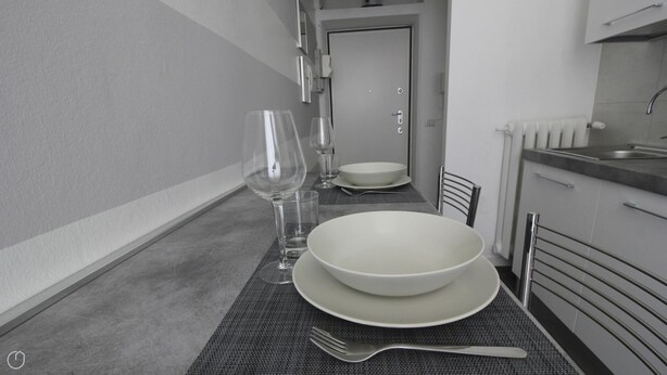 Un coin repas avec une table dressée pour deux personnes, comprenant des assiettes, des bols, des verres et des couverts.