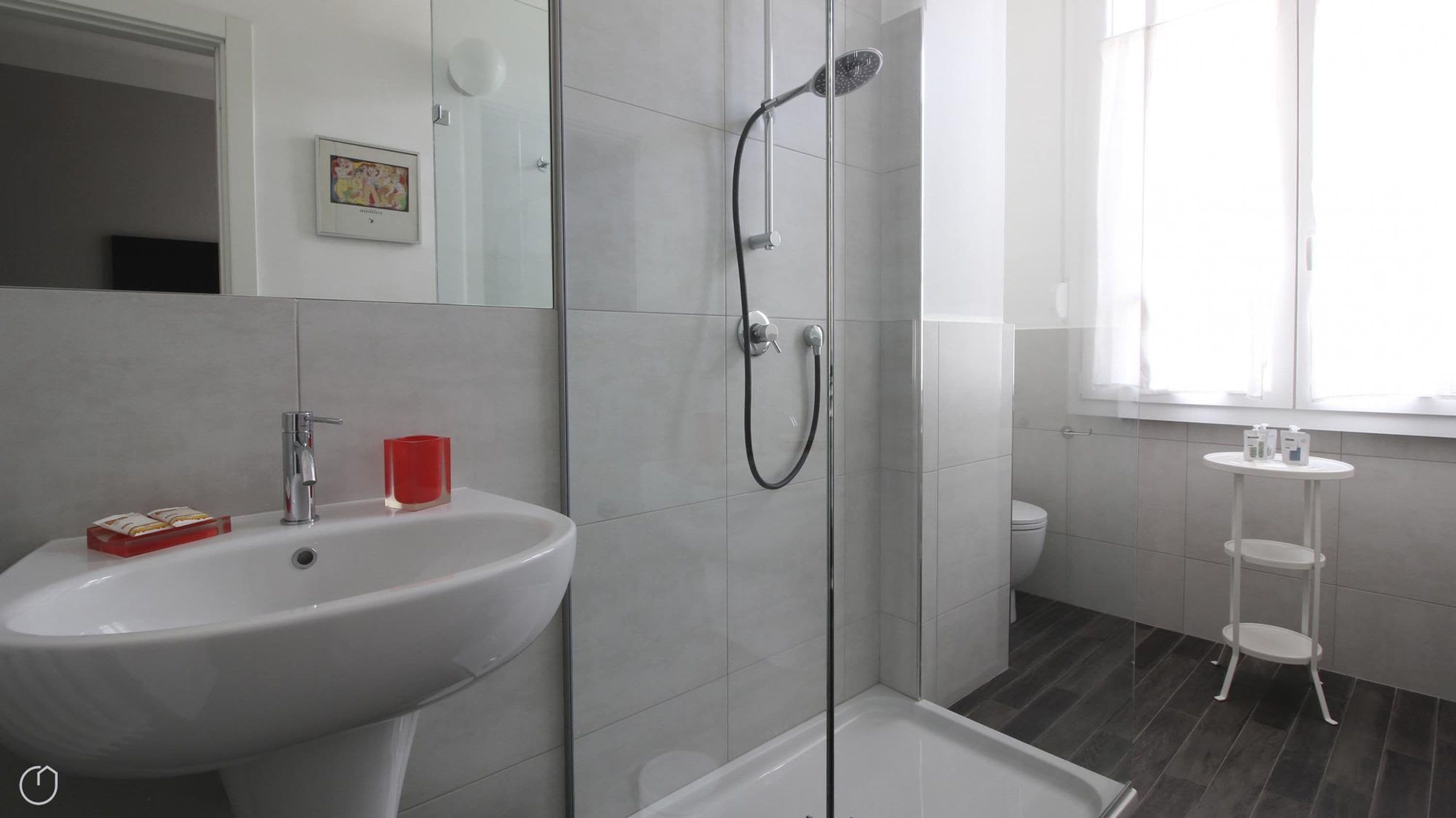 Une salle de bain moderne avec une douche à parois de verre, un lavabo blanc et un petit meuble-lavabo blanc.