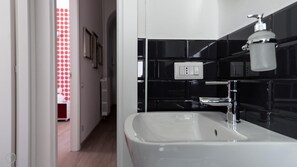 A modern bathroom with a white sink, black tiled walls, and a visible electrical outlet. - Italianway Easy - Melzo 12 - Topolino (Milan)