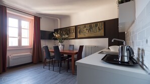 Ett kompakt kök med en matplats, ett element, en tv och konstverk på väggen.