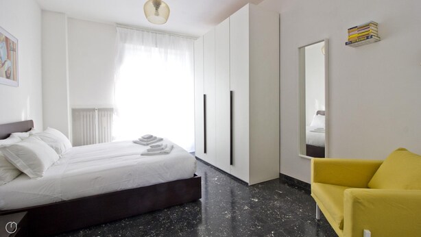 A modern hotel room with a bed, a yellow armchair, a large mirror, and a wardrobe. - Mi-navp112a6 - Naviglio Pavese 112 (Milan)