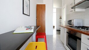 A compact kitchen with a microwave, stove, and a small dining area with a table and chairs. - Mi-navp112a6 - Naviglio Pavese 112 (Milan)
