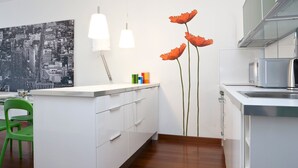 A modern kitchen with white cabinetry, a green chair, a cityscape artwork, and a poppy decoration. - Mi-navp20b1 - Naviglio Pavese 20 II (Milan)