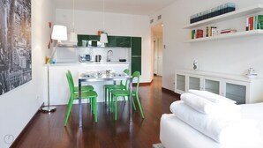 A modern kitchen with green chairs, a dining table, and a white sofa in a living area. - Mi-navp20b1 - Naviglio Pavese 20 II (Milan)