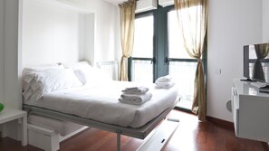 A hotel room with a bed, a desk, a TV, and a window with curtains. - Mi-navp20b1 - Naviglio Pavese 20 II (Milan)