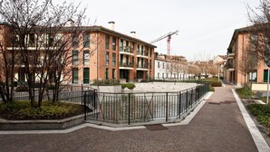 A residential area with brick buildings, a paved walkway, and a small water feature. - Mi-navp20b1 - Naviglio Pavese 20 II (Milan)