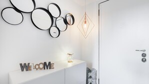 A modern interior with a white console table displaying 'WELCOME' letters, a geometric light fixture, and multiple circular mirrors on the wall. - Italianway Easy - Passeroni 2 (Milan)