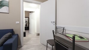 A compact living space with a kitchenette, a dining area with a table and chairs, and a sofa. - Italianway Easy - Petrocchi 48 (Milan)