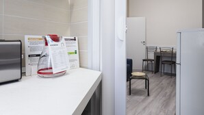 A kitchenette with a refrigerator, a sink, and a countertop with a water dispenser and informational signs. - Italianway Easy - Petrocchi 48 (Milan)