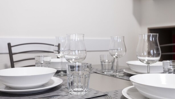 A dining table set with white plates, clear glasses, and a metal chair. - Italianway Easy - Petrocchi 48 (Milan)