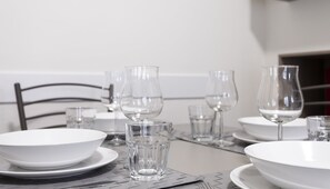 A dining table set with white plates, clear glasses, and a metal chair. - Italianway Easy - Petrocchi 48 (Milan)