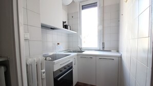 Cuina petita amb armaris blancs, forns, fogons i un rentapeus.