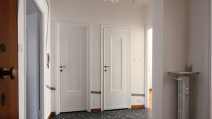 Un passadís amb dues portes blanques, una porta de fusta a l'esquerra i un radiador a la dreta.