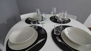 Taula de menjador coberta amb plats blancs, sotsplats negres i gots de vidre transparent.