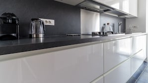 A modern kitchen with a black countertop, stainless steel appliances, and white cabinetry. - Mi-pich19a5 - Pichi 19 (Milan)