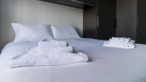 A neatly made bed with white linens and towels, a dark wardrobe, and a plain wall. - Mi-pich19a5 - Pichi 19 (Milan)
