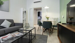 A modern living room with a sofa, coffee table, and a dining area with chairs and a table. - Italianway Easy - Piero Della Francesca 74 (Milan)