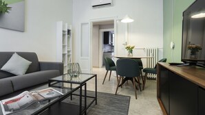 En moderne stue med sofa, sofabord og et spiseområde med stole og bord.